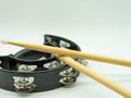 Wooden drumsticks on a black tambourine on white background, with space at the top of the image for text. Concept musical Royalty Free Stock Photo