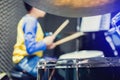 Wooden drumsticks in hands of Asian kid wearing blue and yellow t-shirts to learning and play drum set in music room Royalty Free Stock Photo