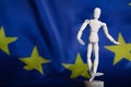 Wooden dummy figurine on European flag. Royalty Free Stock Photo