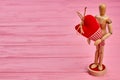 Wooden dummy holding red fabric heart. Royalty Free Stock Photo