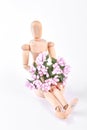 Wooden dummy sitting with flowers. Royalty Free Stock Photo