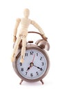 Wooden dummy sitting on old-styled alarm clock.