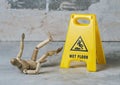 wooden dummy slipped and fell in a puddle with splashing water near a warning sign wet floor Royalty Free Stock Photo