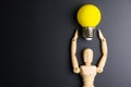 Wooden dummy toy and light bulb on black background with copy sp Royalty Free Stock Photo