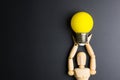 Wooden dummy toy and light bulb on black background with copy sp Royalty Free Stock Photo