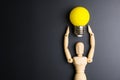 Wooden dummy toy and light bulb on black background with copy sp Royalty Free Stock Photo