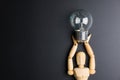 Wooden dummy toy and light bulb on black background with copy sp Royalty Free Stock Photo