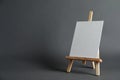 Wooden easel with blank canvas board on dark background, space for text.