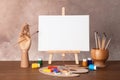 Wooden easel with blank canvas board and painting tools for children on table Royalty Free Stock Photo