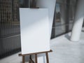 Wooden easel with a blank white canvas near office building. Royalty Free Stock Photo