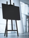 Wooden easel with a blank white canvas in office interior. Royalty Free Stock Photo