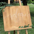 Wooden easel with a board. On the board written white paint - Welcome