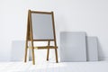 Wooden easel standing in an empty white room Royalty Free Stock Photo