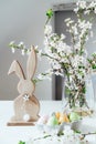 Wooden Easter bunny with blooming tree branch with flowers in the vase and colored easter eggs in container on the white Royalty Free Stock Photo