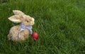 Wooden Easter bunny with red egg on real grass background