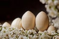 Wooden easter eggs among flowering cherry branches on a rustic table. symbolic composition of the spring holiday for a gift card.