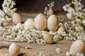 Wooden easter eggs among flowering cherry branches on a rustic table. symbolic composition of the spring holiday for a gift card.