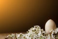 Wooden easter eggs among flowering cherry branches on a rustic table. symbolic composition of the spring holiday for a gift card.