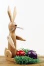 Wooden easter rabbit with nest and two easter eggs on a board