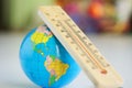 Wooden eco-friendly thermometer and globe on the background of a room or classroom interior.