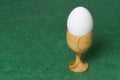 Wooden egg cup holder with white egg on green table Royalty Free Stock Photo
