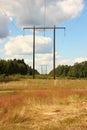Wooden electrical tower in grass field with clouds Royalty Free Stock Photo