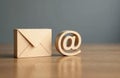 Wooden email symbol alongside envelope. Digital communication, internet, virtual message, online concept. Wooden objects on table Royalty Free Stock Photo
