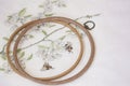 Wooden embroidery hoop with fragment of a colorful cross-stitch embroidery on fabric close-up, summer ornament