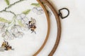 Wooden embroidery hoop with fragment of a colorful cross-stitch embroidery, summer flower ornament. Top view Royalty Free Stock Photo