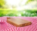 Wooden empty board over picnic cloth on a grass. Royalty Free Stock Photo