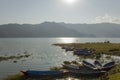 Wooden empty boats at the shore against the backdrop of mountains and a lake with a sunny path Royalty Free Stock Photo