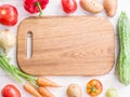 Wooden empty chopping board and vegetables near.