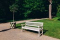 Wooden empty white bench in the city spring park, lush green parkland. Royalty Free Stock Photo