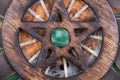 Wooden encircled Pentagram symbol with Green Aventurine in the middle of a circle made of colorful parrot feathers. Five elements