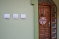 Wooden entrance door with wreath on a house. Electric switches on a wall
