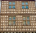 Wooden facade of medieval building with french royal symbolics and tiny mosaic windows. Rustic decadence in Arreau, France