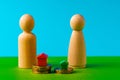 Wooden family with toy house and stack of coins. Savings for house purchase concept