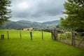 Wooden farm fence, green fields and pastures. Countryside in southern France in the foothills of the Pyrenees mountains Royalty Free Stock Photo