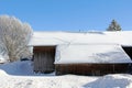 A wooden farmhouse in winter with animal tracks on the snow-covered roof