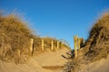 Wooden fence and dry grass on beach on clear blue sky. Entrance to beach. Sunny beautiful day on ocean coast. Royalty Free Stock Photo