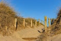 Wooden fence and dry grass on beach on clear blue sky. Entrance to beach. Sunny beautiful day on ocean coast. Royalty Free Stock Photo