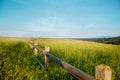 Wooden fence in a grass field against a blue sky. Royalty Free Stock Photo