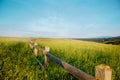 Wooden fence in a grass field against a blue sky.