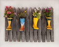 Wooden fence decoratet with flowers planted in rubber boots