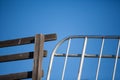 Wooden fence and metal gate juxtaposed against blue sky Royalty Free Stock Photo
