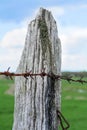 Wooden fence post with rusty barbed wire Royalty Free Stock Photo