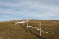 Wooden fence posts and barbed wire marking the property line of a prairie with dried grass and patches of snow under Royalty Free Stock Photo