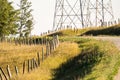 Wooden fence posts line the curve or a rural gravel road overlooking a distant transmission tower in Rocky View County Alberta Royalty Free Stock Photo