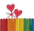 Wooden fence in rainbow colors and two lollipops in heart shape