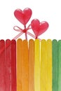 Wooden fence in rainbow colors and two lollipops in heart shape Royalty Free Stock Photo